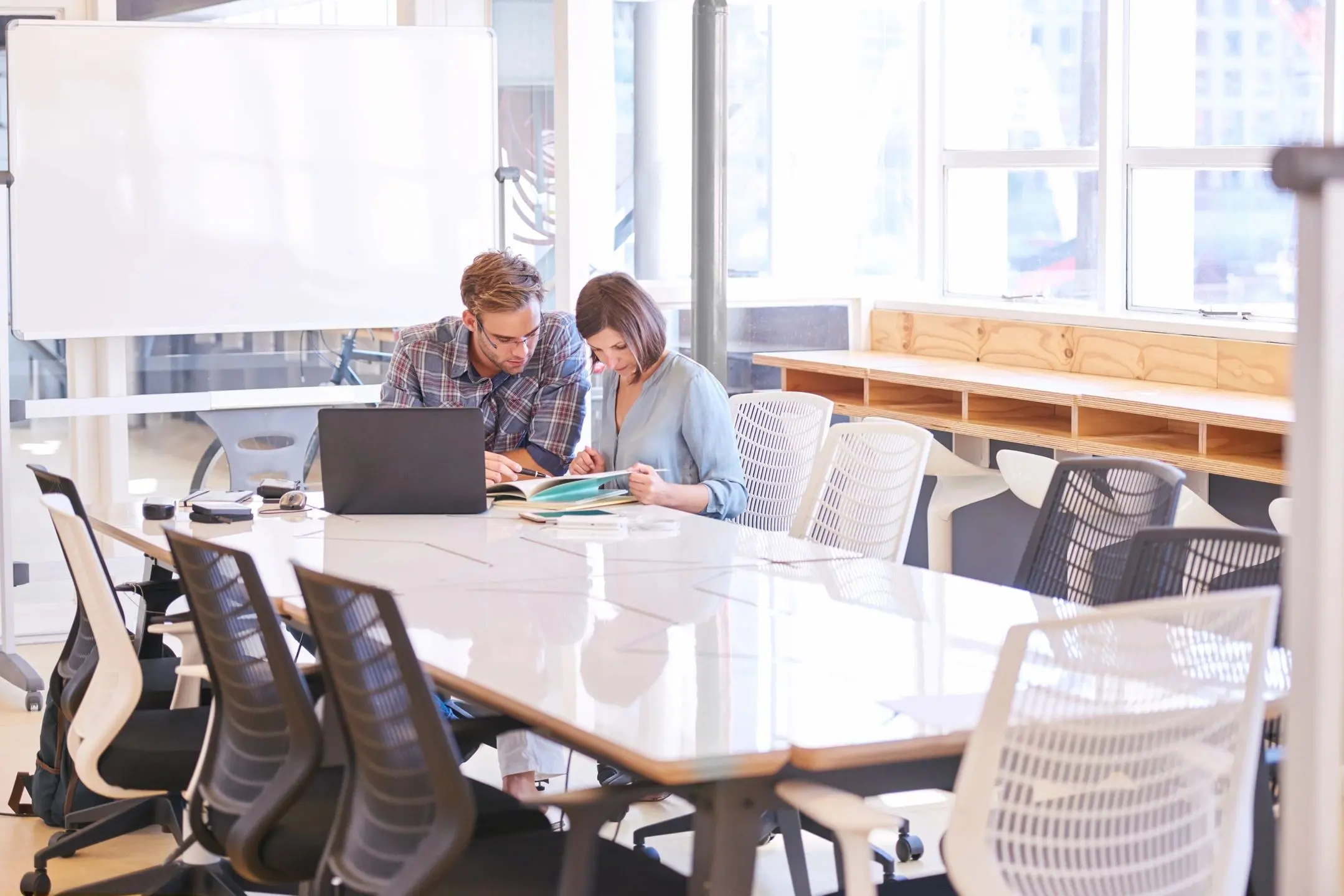 Two colleagues collaborating at a conference table in a modern office.